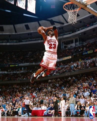 A basketball player in a white number 23 jersey leaping toward the hoop with the ball.