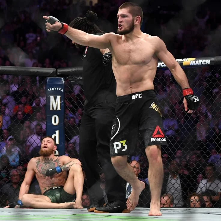 A mixed martial arts fighter in black shorts pointing across the octagon.